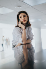 Fototapeta premium A business person on a call sits by a glossy desk in a bright office. The image conveys focus, calm, and everyday work life among associates.