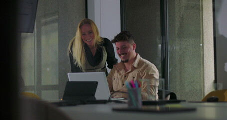 Coworkers celebrate success with cheerful high five in front of laptop during office meeting, smiling and standing together in modern workplace