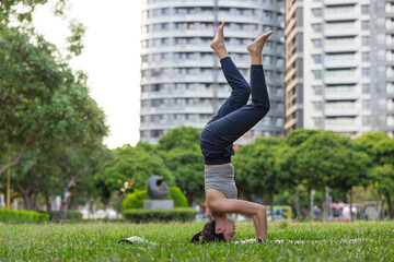 Woman practicing handstand balance pose at park
