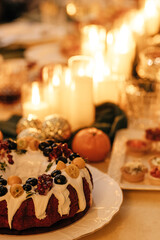 Festive dessert cake adorned with fresh berries and citrus fruits, elegantly displayed on a table surrounded by glowing candles and holiday ambiance