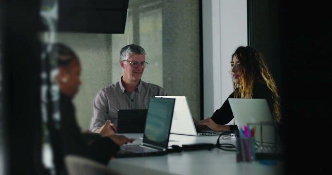 Coworkers quietly concentrate on laptop tasks during team meeting in bright office environment with natural daylight and modern collaborative setup - Powered by Adobe