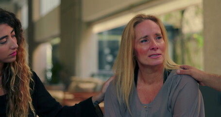 Crying woman comforted by group members during emotional moment in therapy session, expressing pain...