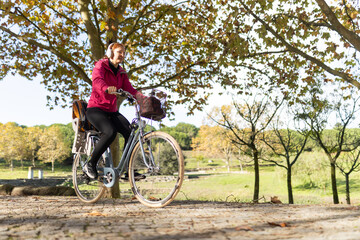 Naklejka premium Woman riding bicycle enjoying autumn park cycling activity