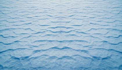 Abstract texture of undulating snow surface showcasing intricate natural patterns formed by wind and cold weather conditions, creating a serene winter backdrop with subtle blue hues