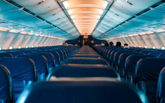 Interior of Passenger Airplane Cabin with Rows of Blue Seats and Aisle - Powered by Adobe