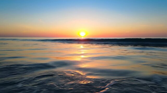 Golden sunrise over gentle ocean waves creates a peaceful, calming scene for travel and relaxation