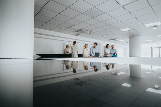 A group of colleagues gather near a reception desk in a bright, contemporary office.