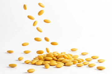 Falling yellow supplement tablets. Medicine. Vitamins. White background.