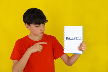 bullying concept. Teenager pointing to the word written in a notebook.