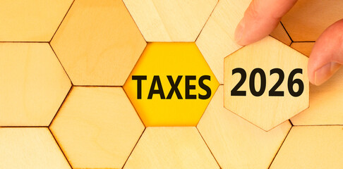 Taxes 2026 new year symbol. Concept words Taxes 2026 on beautiful wooden puzzles. Beautiful wooden puzzles background. Businessman's hand. Business and taxes 2026 new year concept. Copy space.