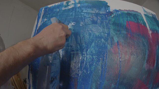 Wasser wird mit Spr&uuml;hflasche auf bemalte Leinwand gespr&uuml;ht &ndash; weitwinklige Studioszene mit Mixed-Media-Texturen, Acrylfarbe und kreativem Malprozess