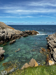 Clear turquoise coastal water with rocky shoreline under a blue sky
