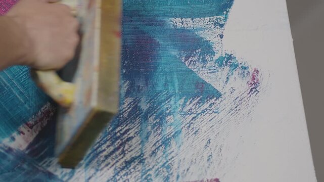 Leichte Spachtelbewegungen auf bemalter Leinwand &ndash; verwischte Acrylfarbe, dynamische Texturen und kreativer Malprozess im Kunststudio