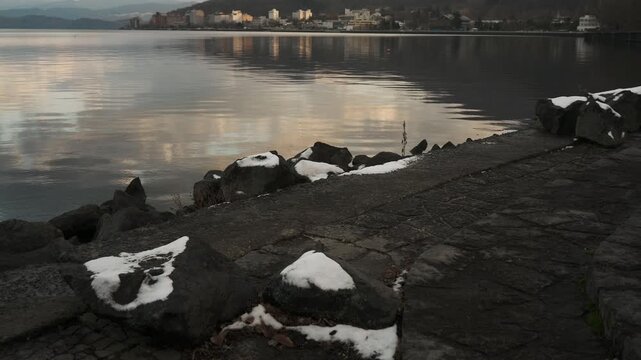鏡面の水面とゴツゴツした岩のある晩秋の湖畔