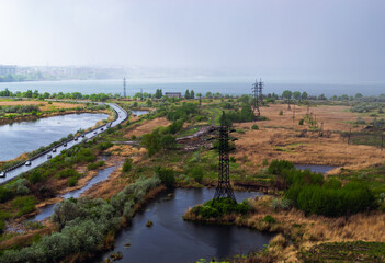 Heavy rain over the lake and the road behind the power line in the field