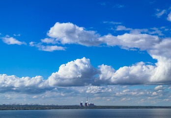 Industrial power plant by lake under blue sky