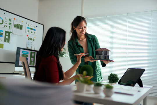 Architect women discussing sustainable real estate home model in office