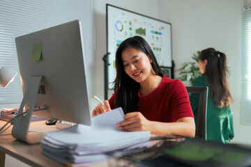 Asian woman working late with documents and computer