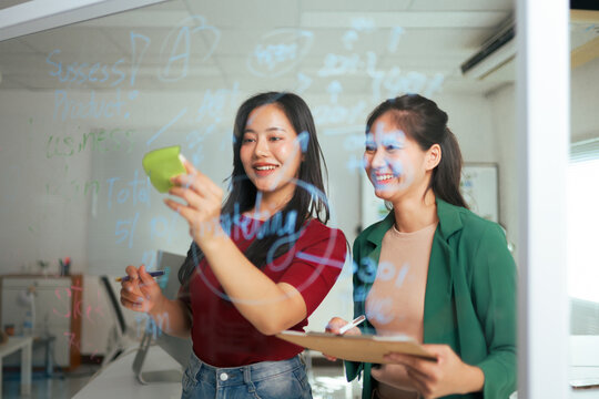 Women professionals brainstorming ideas on a transparent board