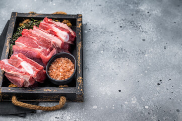 Fresh Raw lamb rib cuts, mutton meat with rib bone in wooden board. grey background. top view