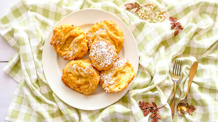 Pastry fritters with powdered sugar on checkered tablecloth