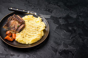 Braised beef short ribs resting on a bed of creamy mashed potatoes, creating an inviting culinary scene. black background. top view