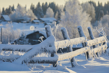 Wooden fence covered in snow and frost in winter