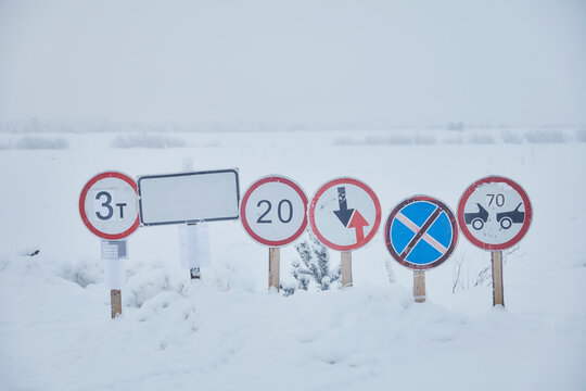 Road signs at an ice crossing in the snow across a river in winter