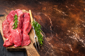 Beautifully arranged raw horse meat slices on a wooden platter, showcasing its appealing color and texture, perfect for cooking inspiration. brown background. top view