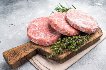 Frozen raw Hamburger beef Patty, uncooked mincemeat. grey background. top view