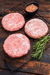 Frozen Meat patties ready for grilling, forcemeat of pork and beef for burgers. wooden background. top view