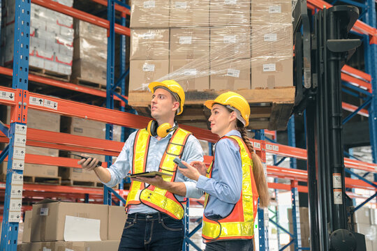 Caucasian man, woman warehouse supervisor discuss and use tablet check package with forklift driver worker load box on shelf, product distribution inventory management,Logistics shipping business plan