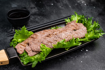 Sizzling yakiniku wagyu bees strips, featuring an array of marinated meats and fresh vegetables, grilled to perfection. A delightful Japanese BBQ. black background. top view