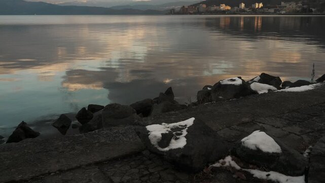 鏡面の水面とゴツゴツした岩のある晩秋の湖畔