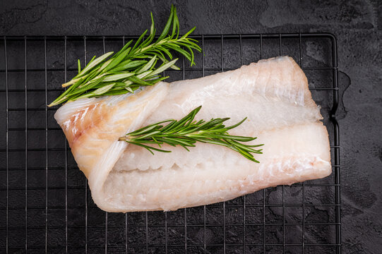 Uncooked Atlantic cod fillet, raw fish ready to be seasoned and transformed into a delicious meal. black background. top view