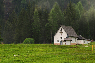 the little church of the crucifix at the beginning of San Nicol&ograve; valley in a foggy morning, Val di Fassa, Dolomites, Italy