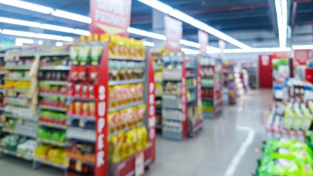 Blurred background of interior of supermarket store aisle with various products on shelves and a prominent "Super Promo!" sign. abstract blur of convenience store aisle, fast moving consumer goods.