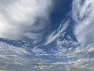 Dramatic sky filled with dynamic high clouds and wispy cirrus streaks against a deep blue background, creating an expressive weather and nature scene with ample copy space.