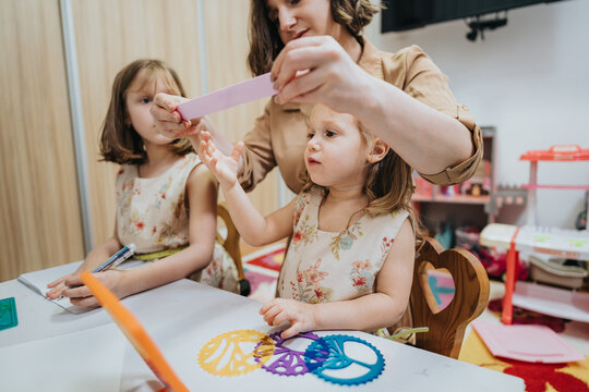 A mother assists her two young daughters with arts and crafts activities at home, fostering creativity and family bonding in a warm and loving atmosphere.