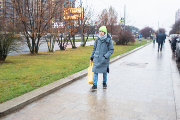 A teenage boy walks with a bag of groceries from the supermarket.
