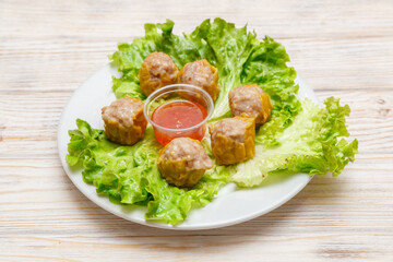 Bouchées de porc avec une sauce piquante sur assiette blanche. Cuisine asiatique. Traiteur asiatique.