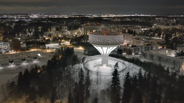 Vantaa.Finland-December 29.2021: Drone shot of the new Hiekkaharju water tower alongside the old one in Vantaa. Nighttime. Awesome cityscape. Wintertime. Camera slowly moving sideways.
