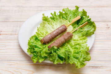 Brochette boeuf fromage sur assiette blanche avec feuille de salade. Cuisine asiatique. Traiteur asiatique.