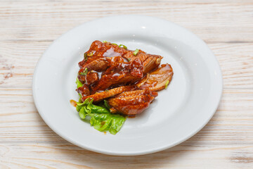 Canard laqué sur assiette blanche. Cuisine chinoise. Traiteur chinois.