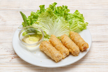 Nems au porc sur assiette blanche avec feuille de salade et sauce. Cuisine asiatique. Traiteur asiatique.