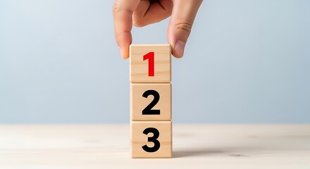 Hand stacking wooden blocks numbered one two three on table