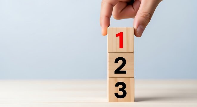 Hand stacking wooden blocks numbered one two three on a light background