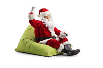 Santa claus playing video games with a joystick and sitting on a beanbag