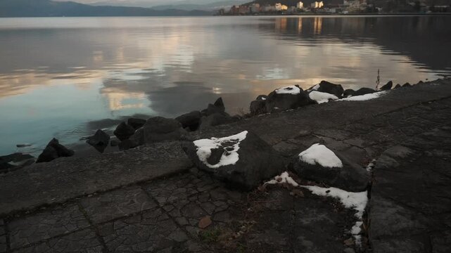 鏡面の水面とゴツゴツした岩のある晩秋の湖畔