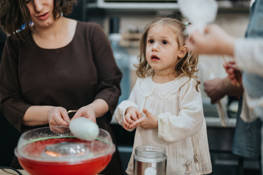 A mother and her young daughter engaged in making handcrafted treats, evoking a warm family atmosphere. A cotton candy machine is shown in a casual home kitchen setting.